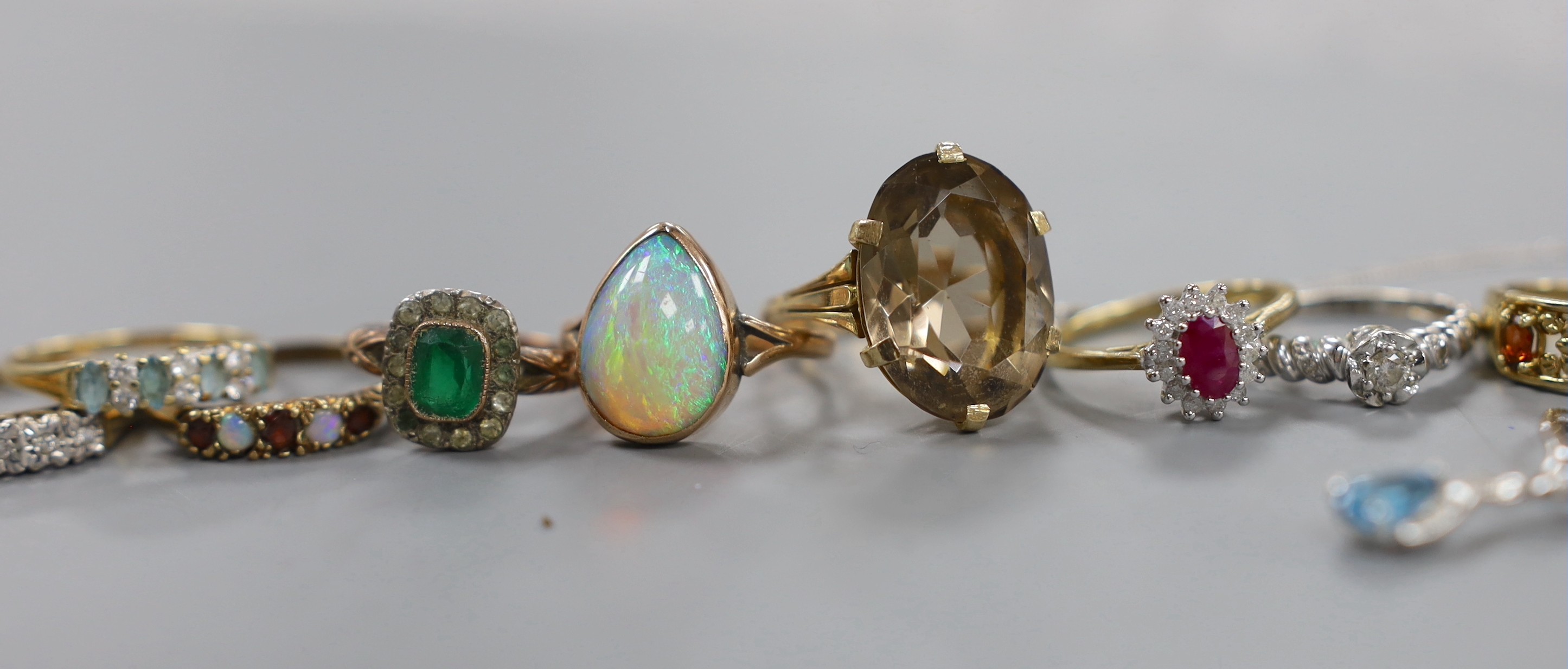 A modern 9ct white gold, blue topaz and diamond set pendant, ten assorted modern 9ct and gem set rings, a yellow metal and opal ring and a quartz set pendant.
